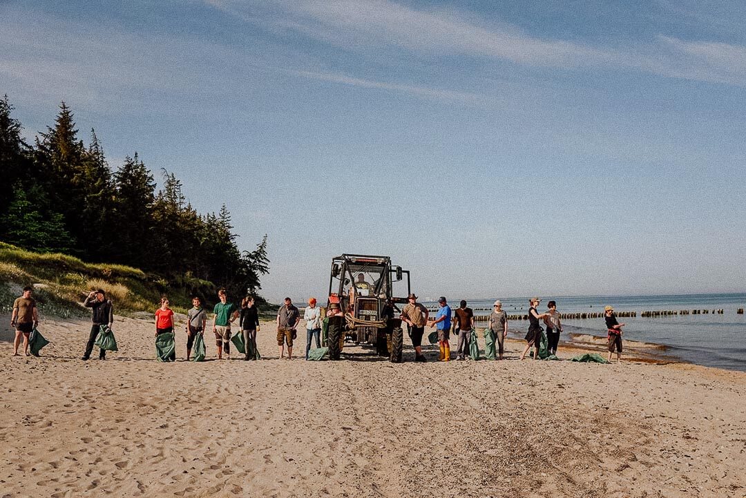Mehrere Personen mit Müllsäcken am Strand.