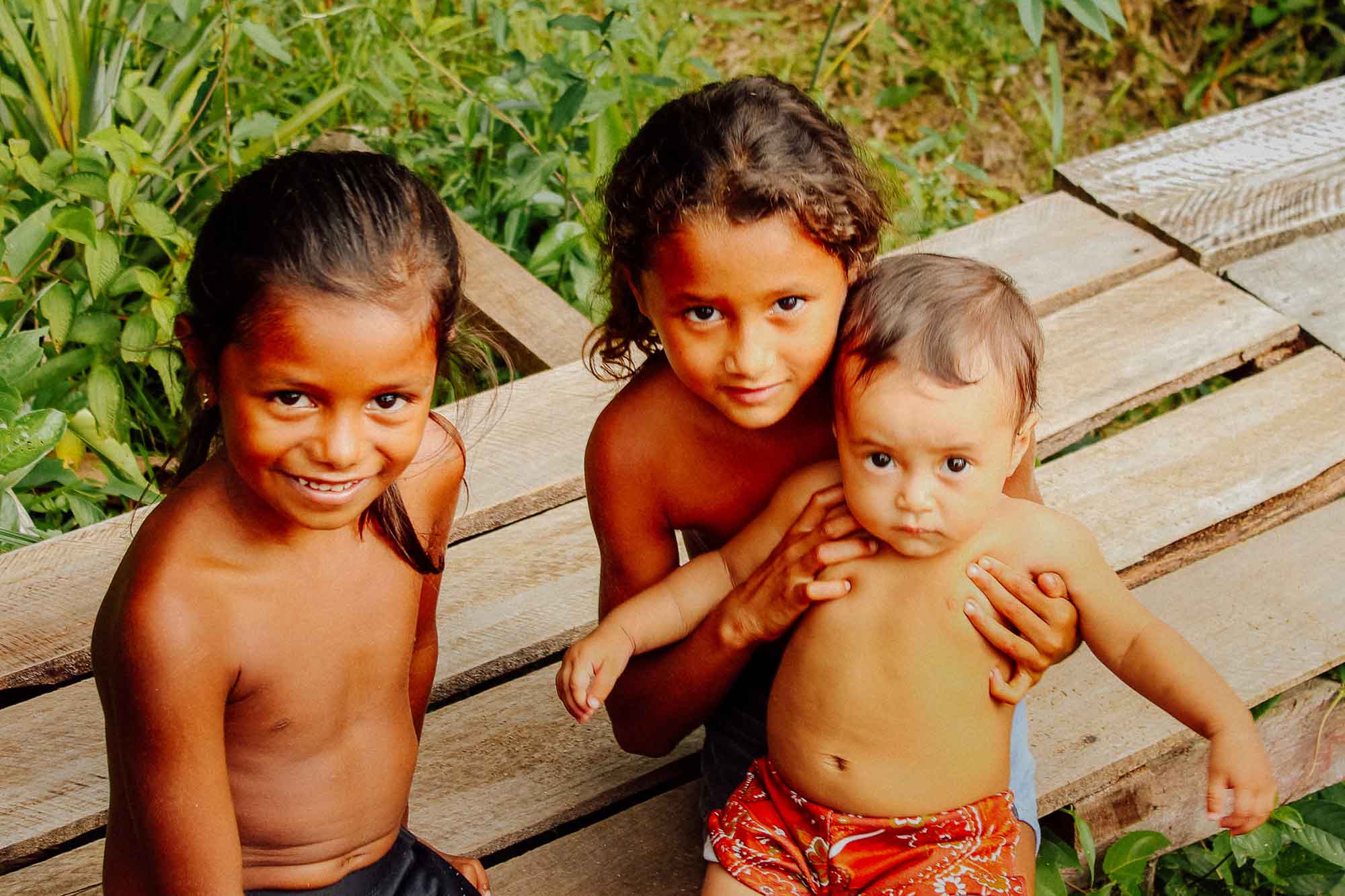 Drei Kinder gucken in die Kamera.