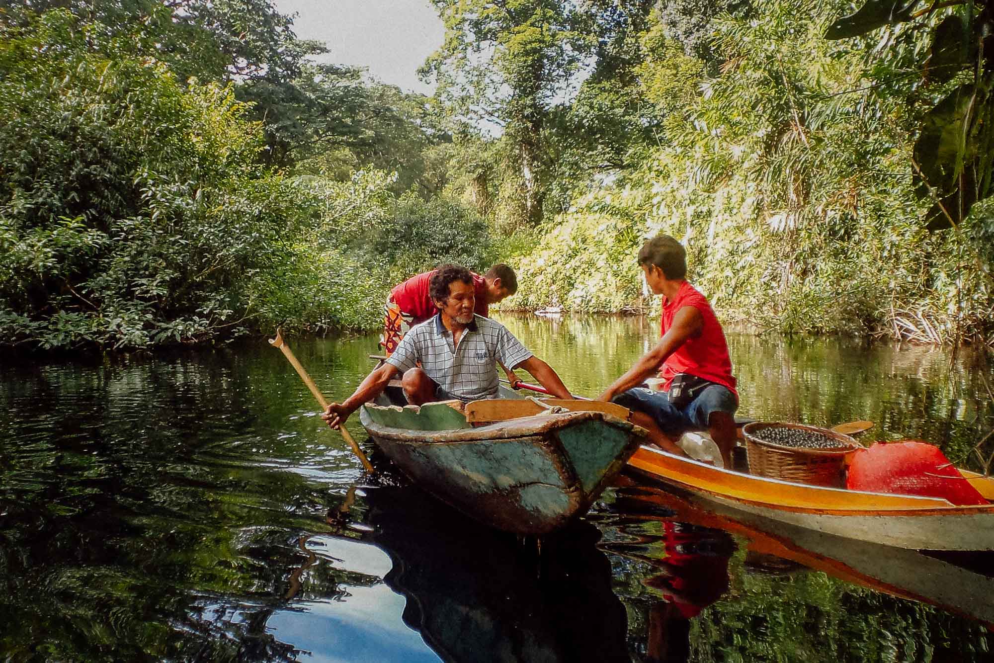 Drei Männer in zwei Kanus auf einem Fluss.